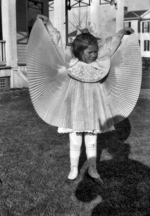 A young girl holding up an accordion pleated skirt