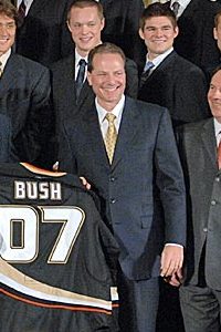 黒いスーツを着たサミュエリ氏が、「Bush 07」と書かれた黒いホッケージャージをジョージ・W・ブッシュ大統領に贈呈している。