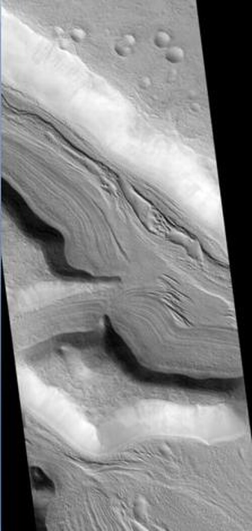 HiRISE が撮影したヒプサス渓谷。尾根はおそらく氷河の流れによるもの。つまり、水氷は薄い岩の層の下にある。