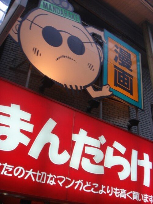 大阪のまんだらけ梅田店の看板。古川益造の漫画風イラストが描かれている。