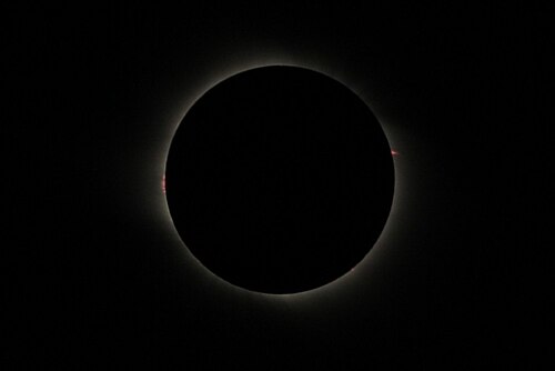 中国酒泉で皆既日食が発生。太陽の両側に赤いプロミネンスが見られる。