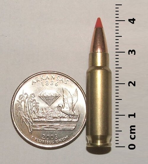 サイズ比較のため、5.7×28mm SS196SR カートリッジを 25 セント硬貨と定規の横に置いた写真。