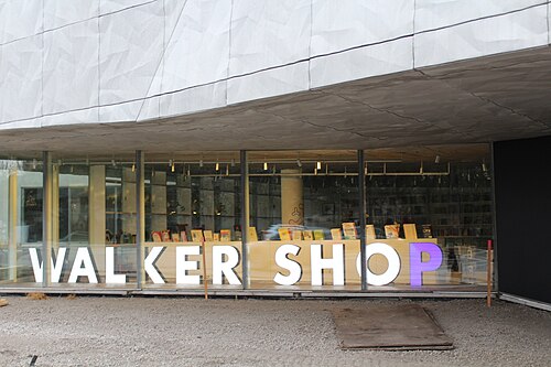 近代的な店舗の窓。大きな照明付きの文字で「Walker Shop」と白で書かれ、P は紫色で書かれている。