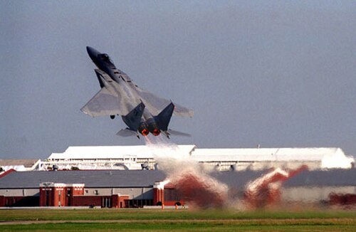 灰色のジェット戦闘機が急角度で離陸し、アフターバーナーをフル稼働させている。エンジンから噴出する高温のガスからもそれがわかる。