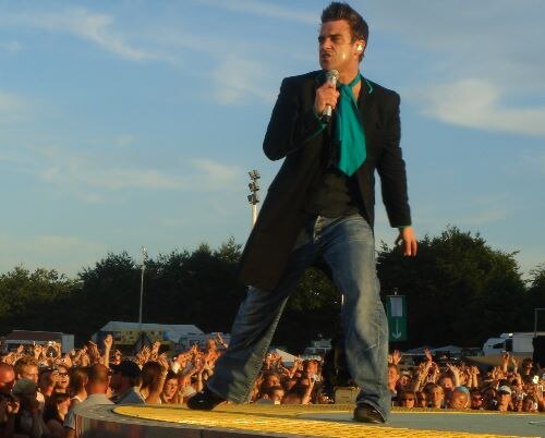 2006 年にステージでライブ演奏しているロビー・ウィリアムズのカラー写真。