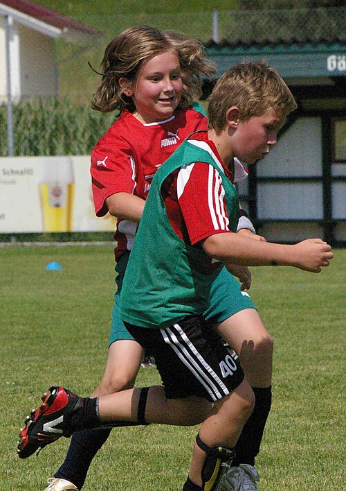 男の子と女の子がサッカーボールを追いかけている