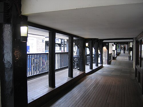 右側に建物の正面、左側に通りを見下ろす柱と手すりがある高架の屋根付き通路