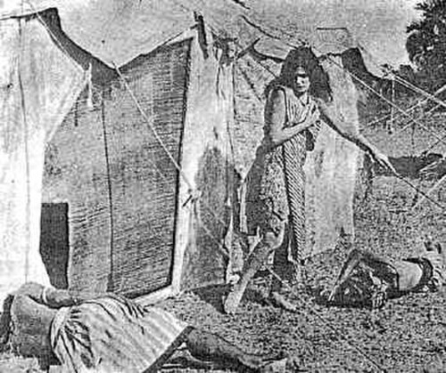 長い黒髪の若い女性がテントの外を歩き、地面で眠っている二人の男性のうちの一人を見下ろしている。彼女はショールと膝丈のドレスだけを身に着けており、腕、ふくらはぎ、足は露出している。