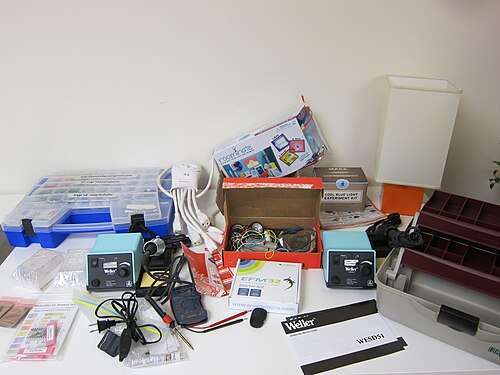 白い壁のテーブルの上に並べられた小型の電子工具と備品
