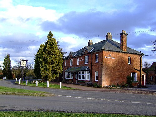 道の曲がり角にある立派なレンガ造りの建物。パブの看板には「Verney Arms」と書かれている。