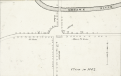 白黒の地図で、建物や道路がシンプルな小さな黒い線で描かれている。右下には「1802年のユティカ」という文字が記されている。