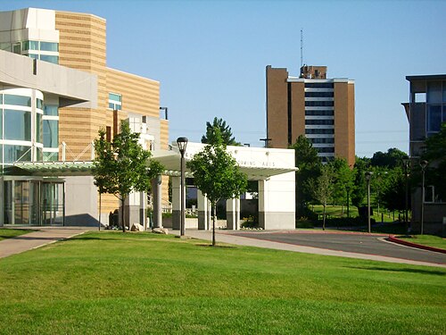 大学のキャンパスの建物。後ろにはレンガ造りの高層寮の建物があります。その上には FM アンテナを備えた支柱付きの鉄製のマストが設置されています。