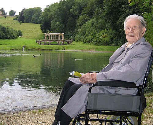 イギリスの田舎の小さな湖の近くにいる車椅子の老人。