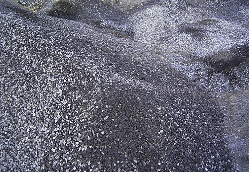 使用済みの頁岩の塊が積み上げられた暗い灰色/銀色の山の写真。