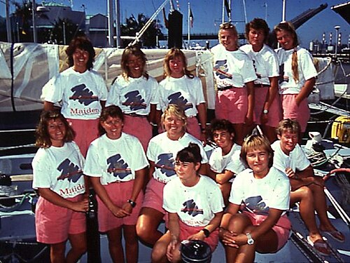 ヨットに乗っている白いTシャツとピンクのショートパンツを着た13人の女性の集合写真