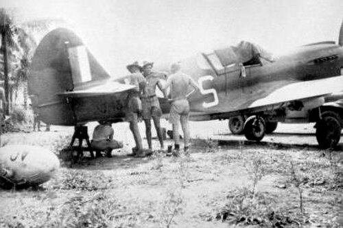 P-40 キティホークの後方3/4ビュー。熱帯装備の4人の男性。