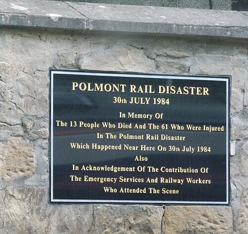 石の壁に取り付けられた、金文字が刻まれた黒い長方形の銘板