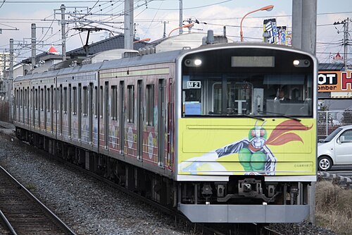 前面に仮面ライダーをあしらった都会の電車