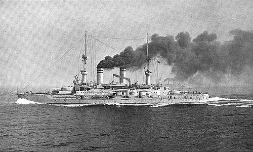 巨大な戦艦が高速で水面を突き進み、煙突からは濃い黒煙が噴き出している。