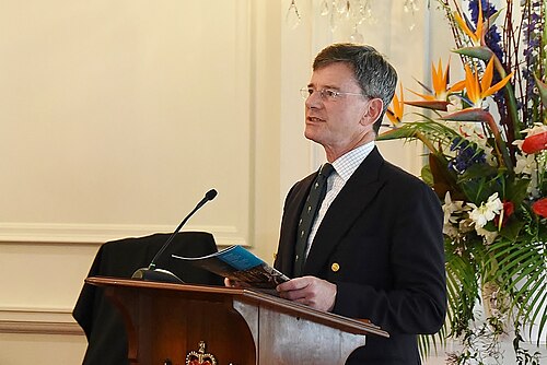 フィンレイソン氏は花を背に演壇で演説している