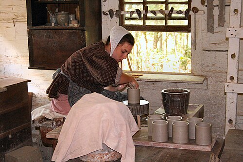 時代衣装を着て陶芸のろくろを回す若い女性