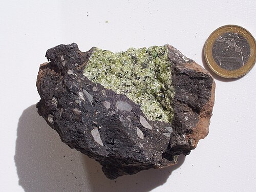 ドイツのヴルカンアイフェルの（暗い）火山弾の中にあるペリドタイト（緑）マントル捕獲岩（大きさを示すために 1 ユーロ硬貨を使用）