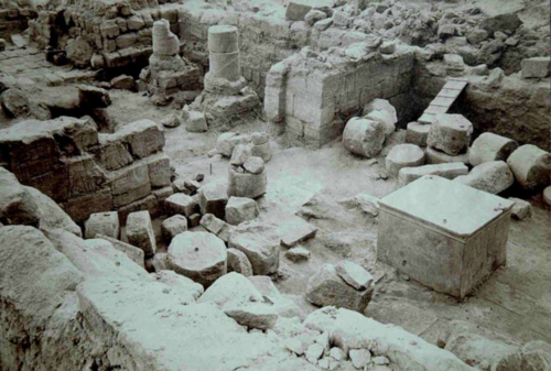瓦礫に覆われた低い寺院の遺跡。中央には大きな立方体の花崗岩のブロックがあります。