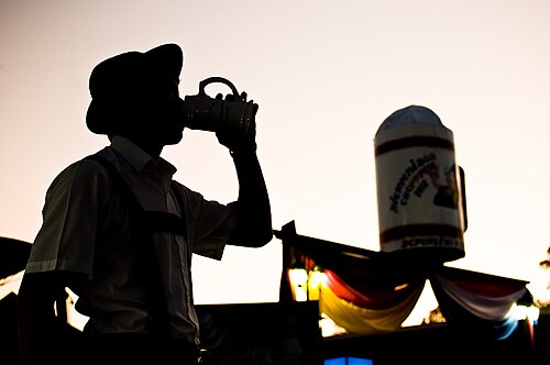 パラグアイ中部、コロニア・インデペンデンシアにあるクラブ・アレマンの前でビールを飲む若い男性。