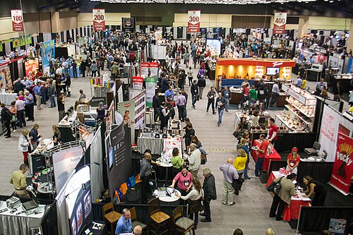 数十ものカラフルなブースに製品が展示され、その間を人々が行き交う展示会の上空からの眺め