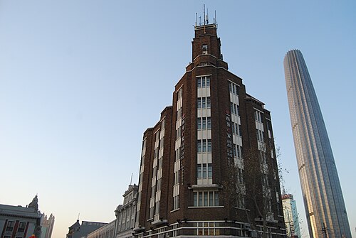1937 年に建てられたガルフ ビルディング (またはポー ハイ ビルディング) は、1960 年代以前は天津で最も高いビルでした。後ろには天津ワールド ファイナンシャル センターが見えます。