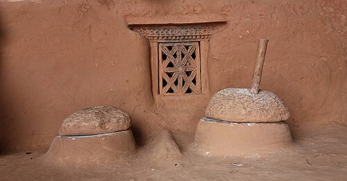 ネパールの田舎の家のポーチにある、ネパール語でジャトと呼ばれる石臼(右)。