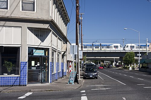 左側の建物と、その背景にある橋を渡るグリーンラインの列車の写真