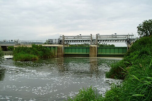 川を横断する鉄製の水門の上には、ガントリーが架かっている。左側には堰がある。