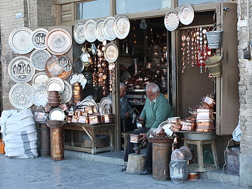 店の前で金属工芸品を作っている二人の男性