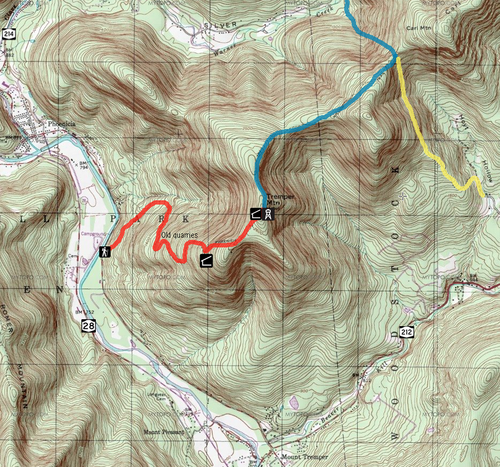 緑と白の背景に茶色の等高線が引かれた地形図。赤、青、黄色のルートが黒と白のアイコンとともに重ねられています。地図の端にある 3 本の道路には、28、212、214 の番号の標識があります。