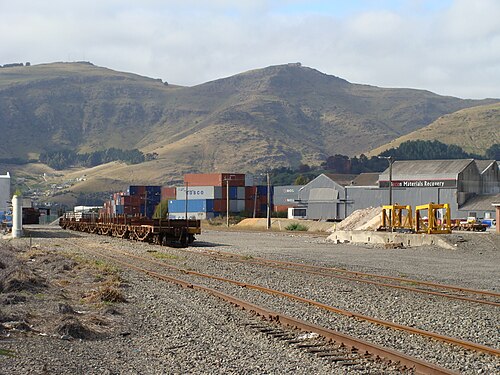 ウールストン鉄道駅: 貨車の側線 (前景)、コンテナ保管ヤード (背景)、積み込みバンク (右)。
