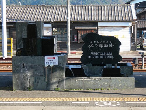 島式ホームにある天然の湧き水を提供する噴水。白い看板には「お飲みください」と書かれています。