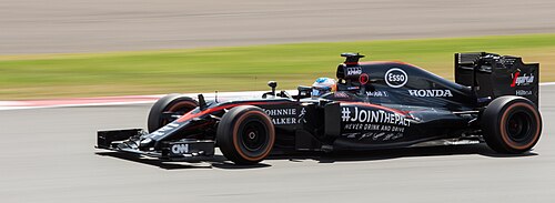 2015年のイギリスグランプリで、フェルナンド・アロンソがマクラーレンMP4-30フォーミュラワンカーを運転している写真。