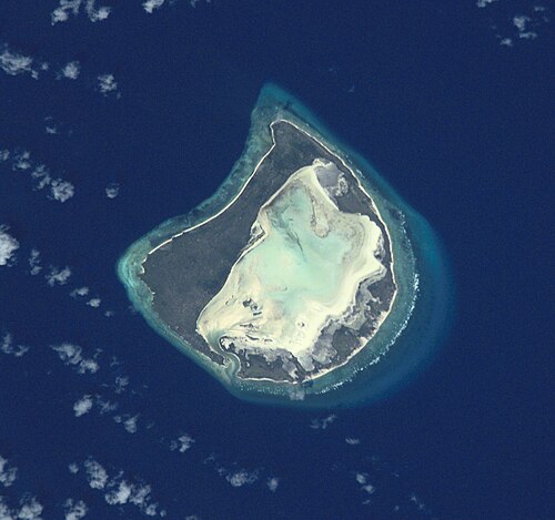 アストーブ環礁、宇宙から少し斜めから見た図。白っぽいラグーンを囲む広い陸地（暗い部分）に注目してください。