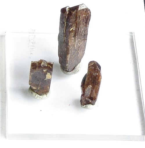 白い背景に3つの柱状の茶色の結晶