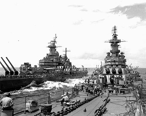 2 隻の大型戦艦がこちらに向かって航行しています。両方の船の甲板に人員が見えます。