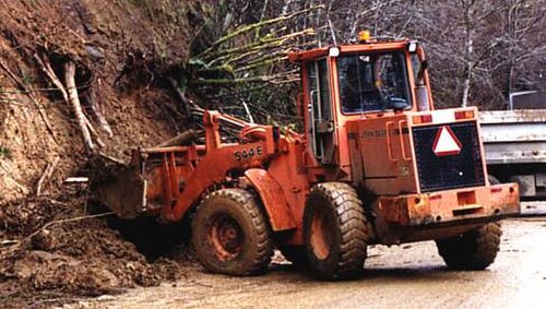 油圧シリンダーで昇降する大型バケットを備えた、車輪式のフロントローダー式トラクター。
