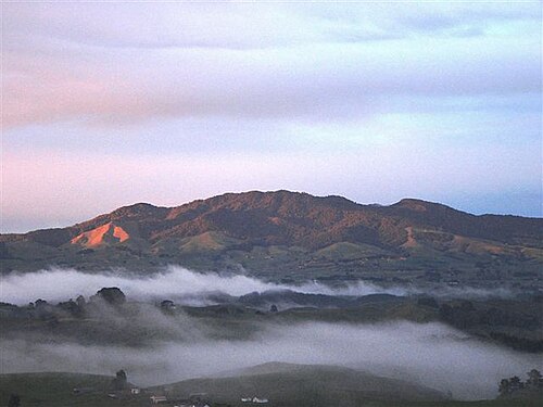 円錐形の山の周りに霧が立ち上る、北から見たマウンガタウタリ。