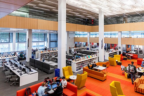明るい照明とテーブルでグループ作業する学生たちで構成された大学図書館
