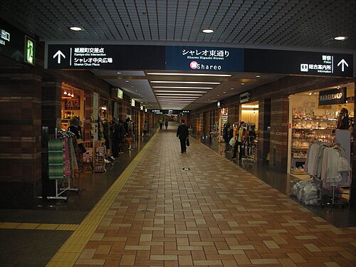 長い廊下の入り口上部には、照明付きの電光看板が設置されている。廊下の両側には、店舗が軒を連ねている。