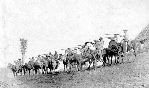 キューバ解放軍の騎手15人が馬に乗っている。指揮官だけマチェーテを振り回しているが、それ以外は全員がカービン銃(おそらくレミントン)を持っている。