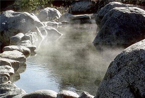 岩の群れに囲まれた湯気の立つ水たまり。