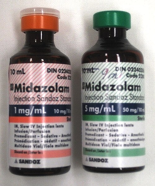 ミダゾラムと書かれた 10 ml ボトル 2 本。左のボトルには赤いラベルが貼られており、1 mg/ml と書かれています。右のボトルには緑のラベルが貼られており、5 mg/ml と書かれています。どちらのボトルにも細かい文字がたくさん書かれています。