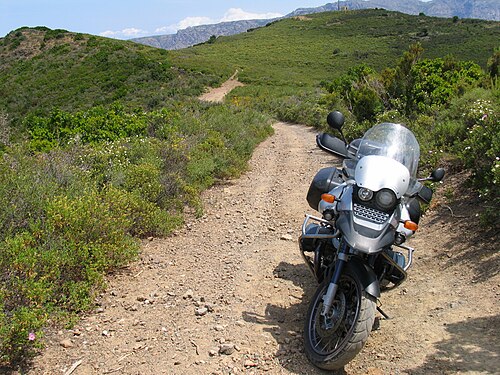 砂利道に駐車されたBMW R1150GS。背景には低木に覆われた山々が見える。