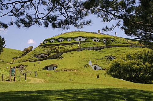 画像は、住宅が建てられた起伏のある緑の丘を示しています。これらは、ロード オブ ザ リングの映画で「ホビット村」の町を形成しました。これらのセットと他のセットは、ニュージーランド北島のワイカト地方にあるマタマタの町の近くに建設されました。